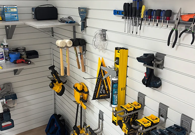 Garage slatwall with hooks and shelves holding power tools and hand tools