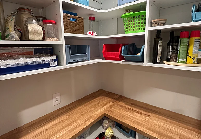 L-shaped pantry with white shelves above a butcher block countertop
