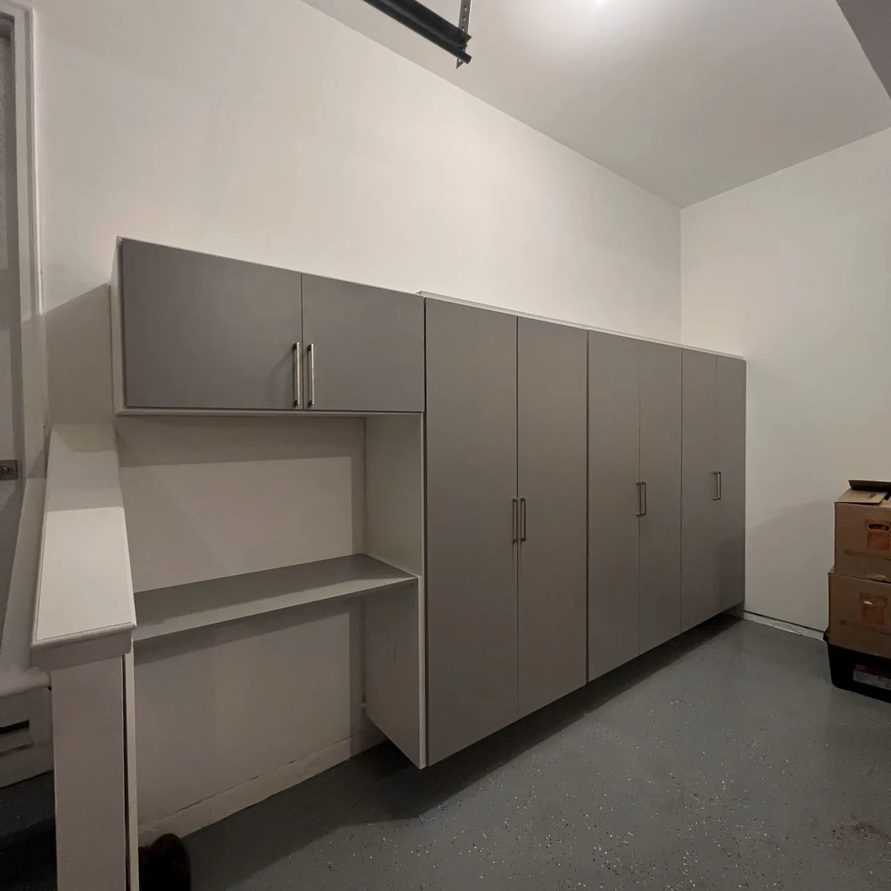 Garage after installation with a long run of gray cabinets and a workbench
