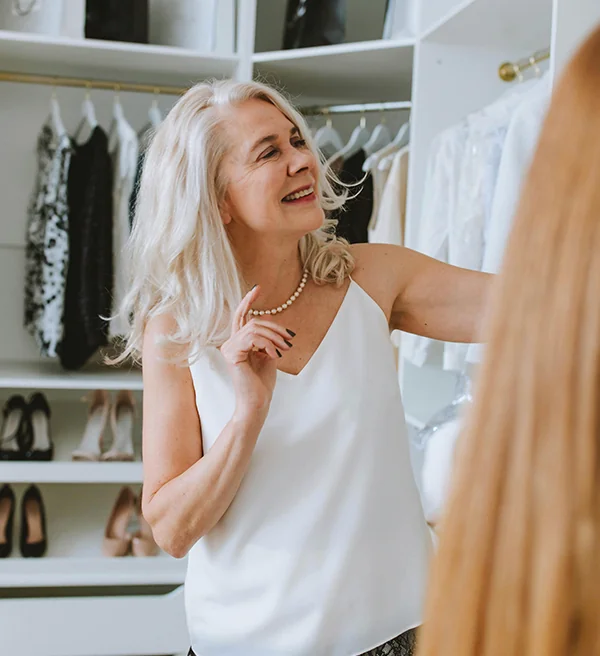 Smiling homeowner choosing an outfit in her organized white closet