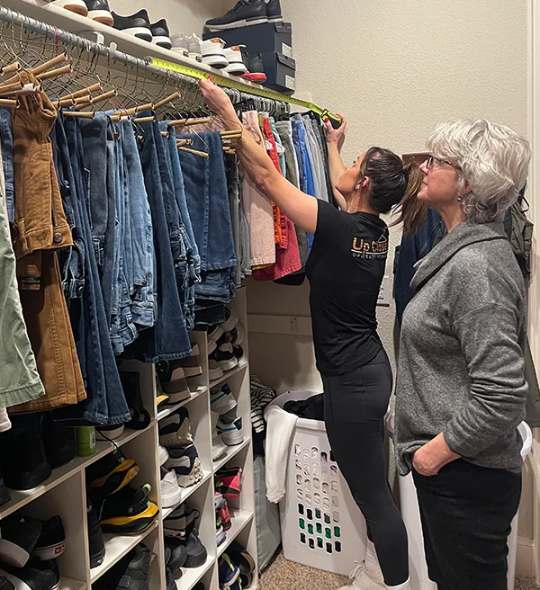 Designer measuring an existing closet while the homeowner looks on