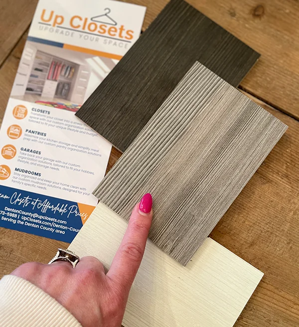 Homeowner comparing wood-grain finish samples next to an Up Closets brochure
