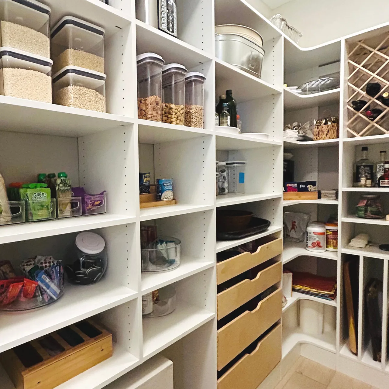 Organized pantry after installation with white shelves, wine storage and drawers